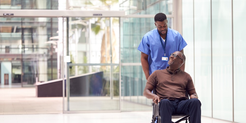 male nurse wheeling happy senior patient