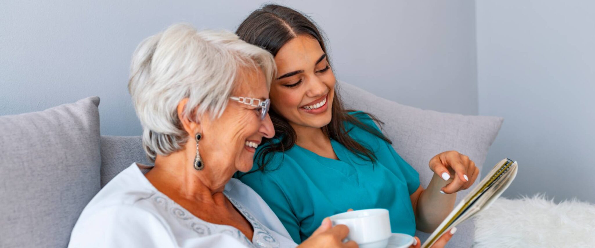 A caregiver shows something to a smiling senior female