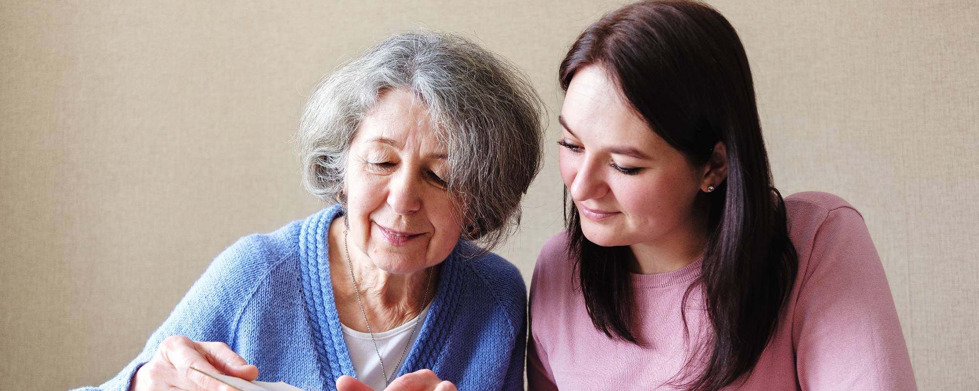 senior lady looking through a photo album with her granddaughter