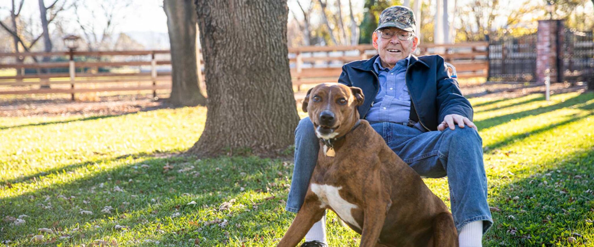 An elderly man sits outside with his dog