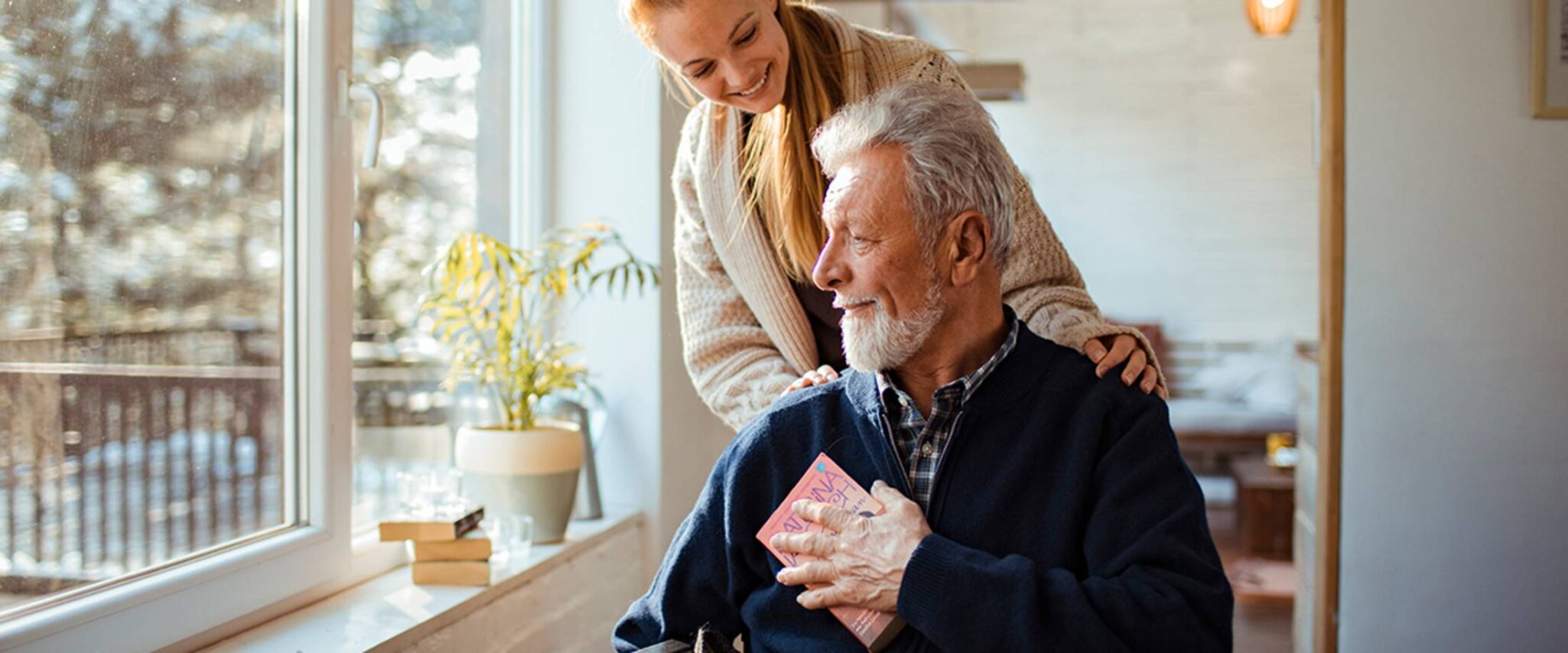 senior man in a wheelchair getting assistance from a healthcare worker