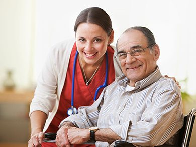 A senior man sitting in a wheelchair with his nurse next to him.