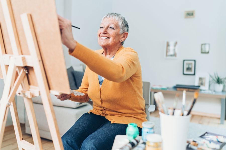 a senior woman paints in a brightly lit studio