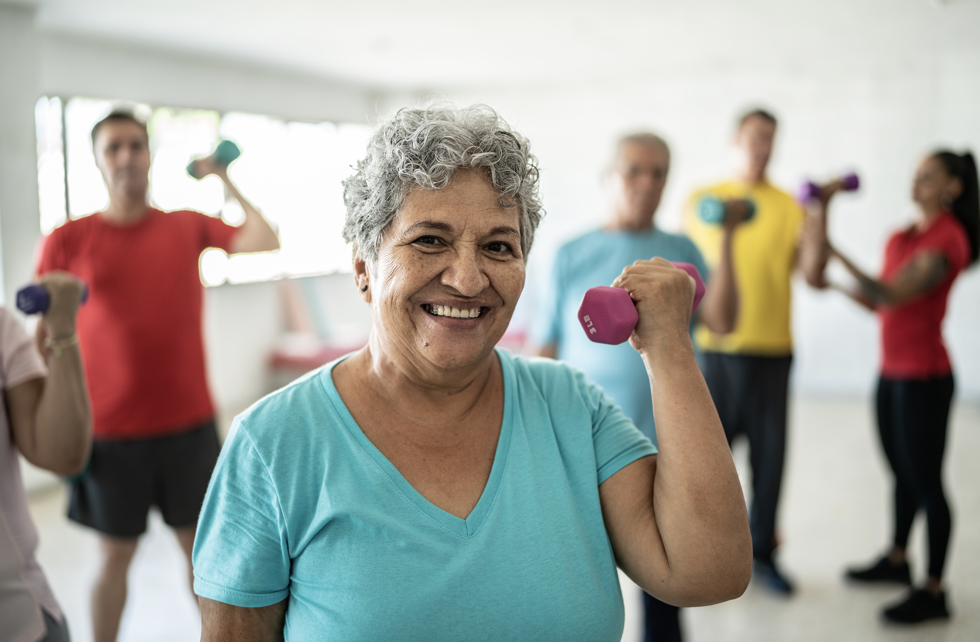 Smiling senior woman holding a dumbbell in a workout class