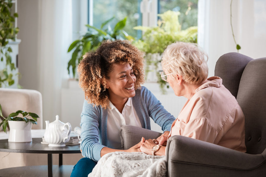 A senior woman holds the hands of a younger adult woman.