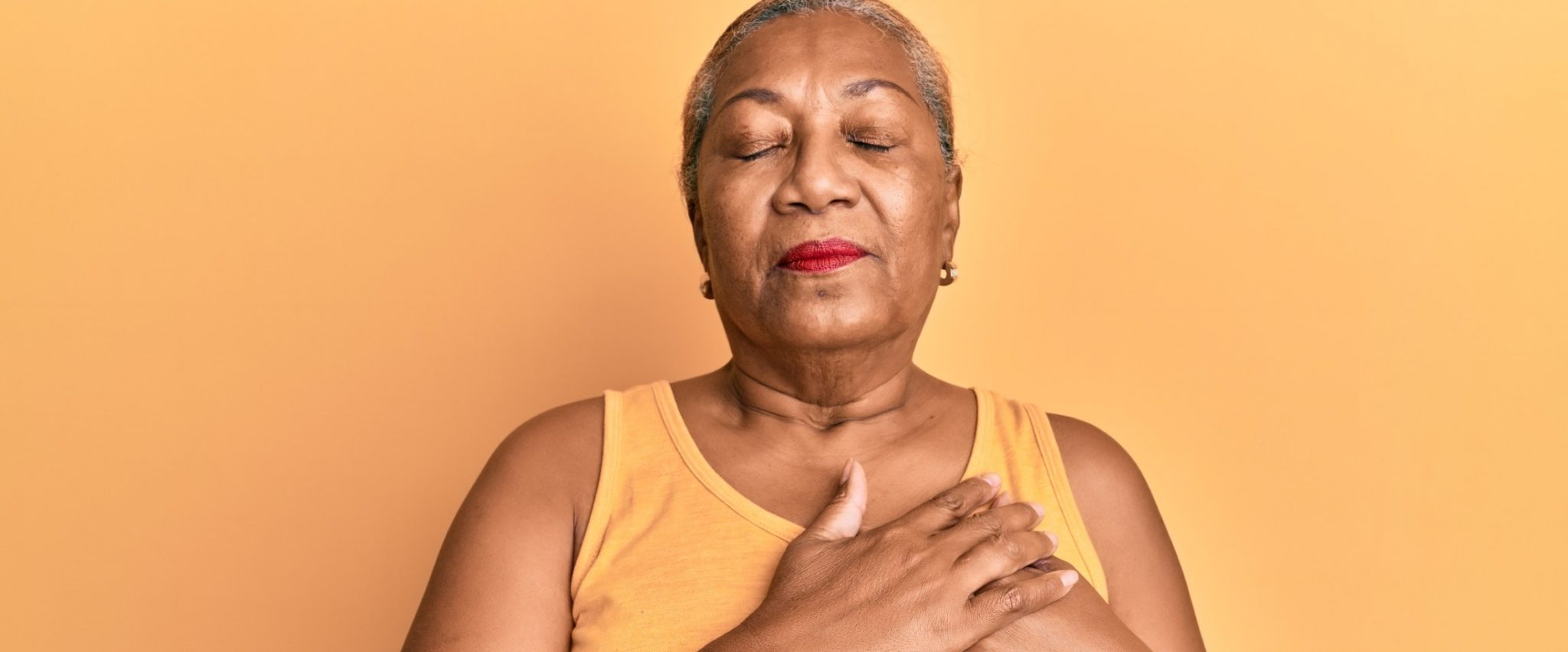 senior lady holds up her hands over her heart