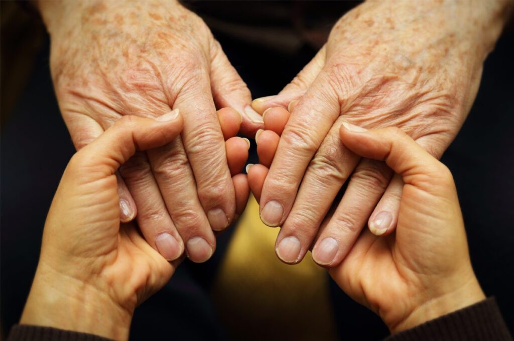 Close up of a senior woman's hands held by a younger woman's hands