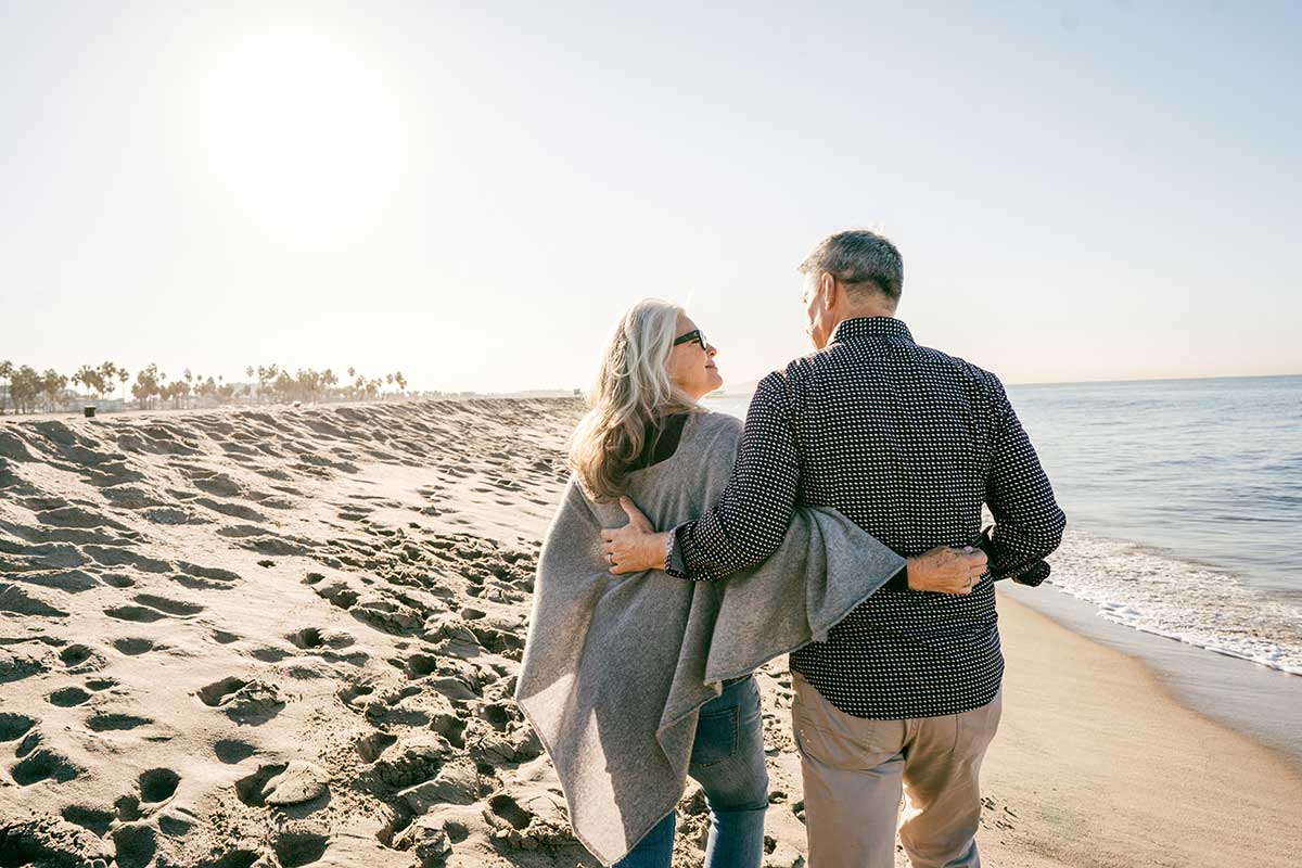 A wife and husband walking down a beach