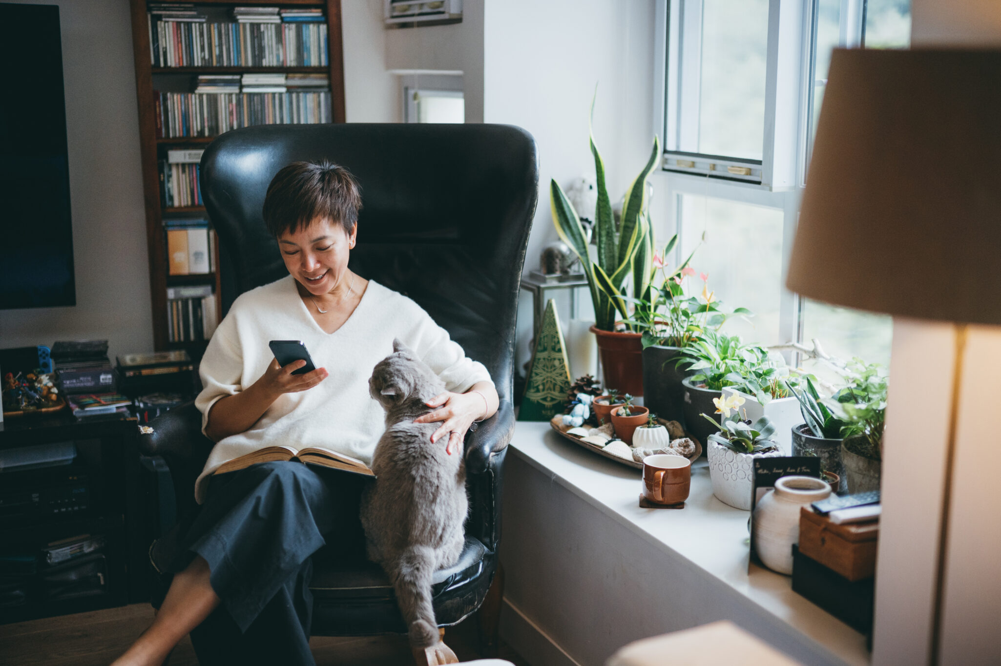 Senior woman using smartphone while sitting in a corner armchair