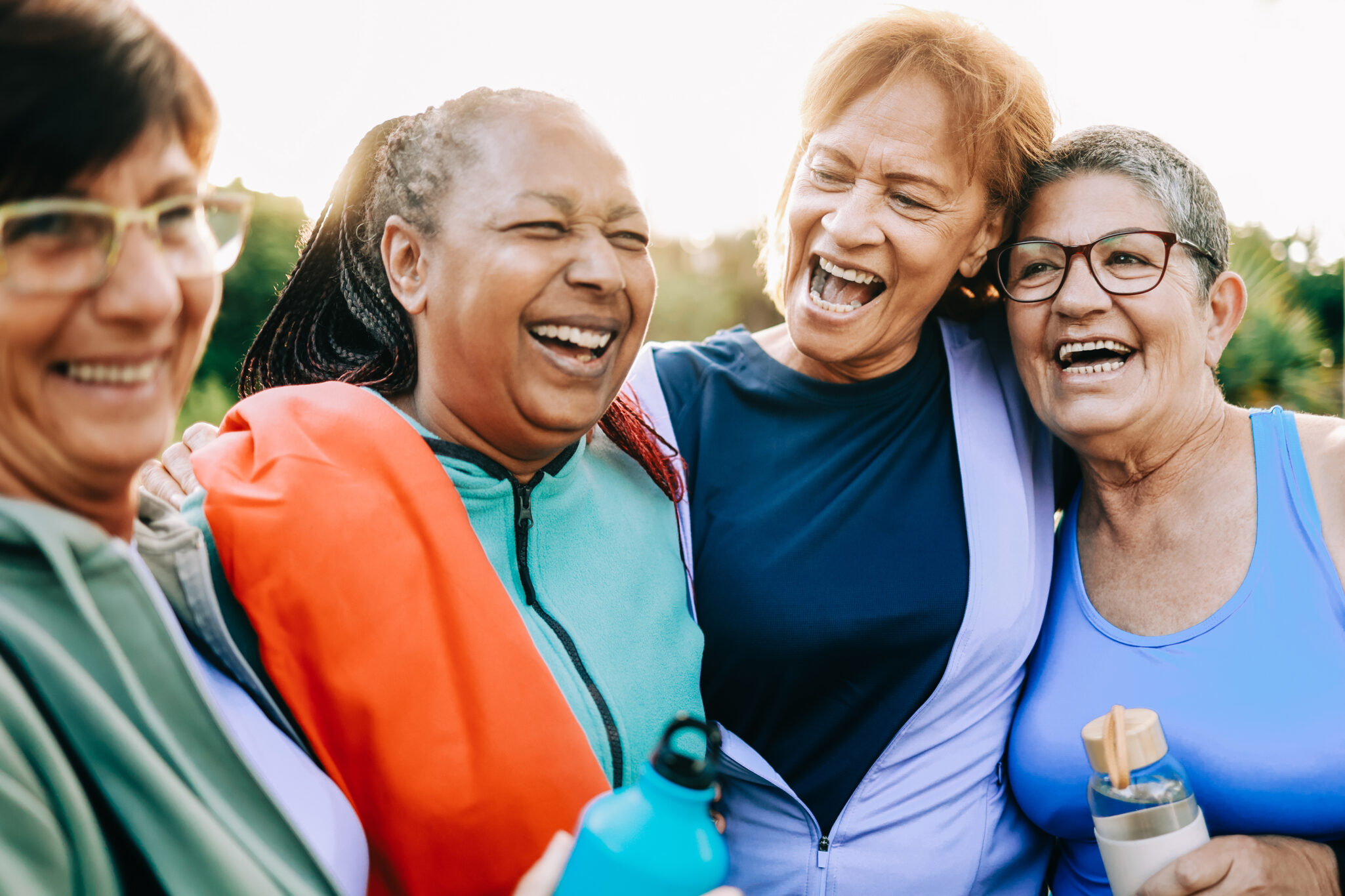 A group of senuior woman laughing and hugging after an outdoor workout