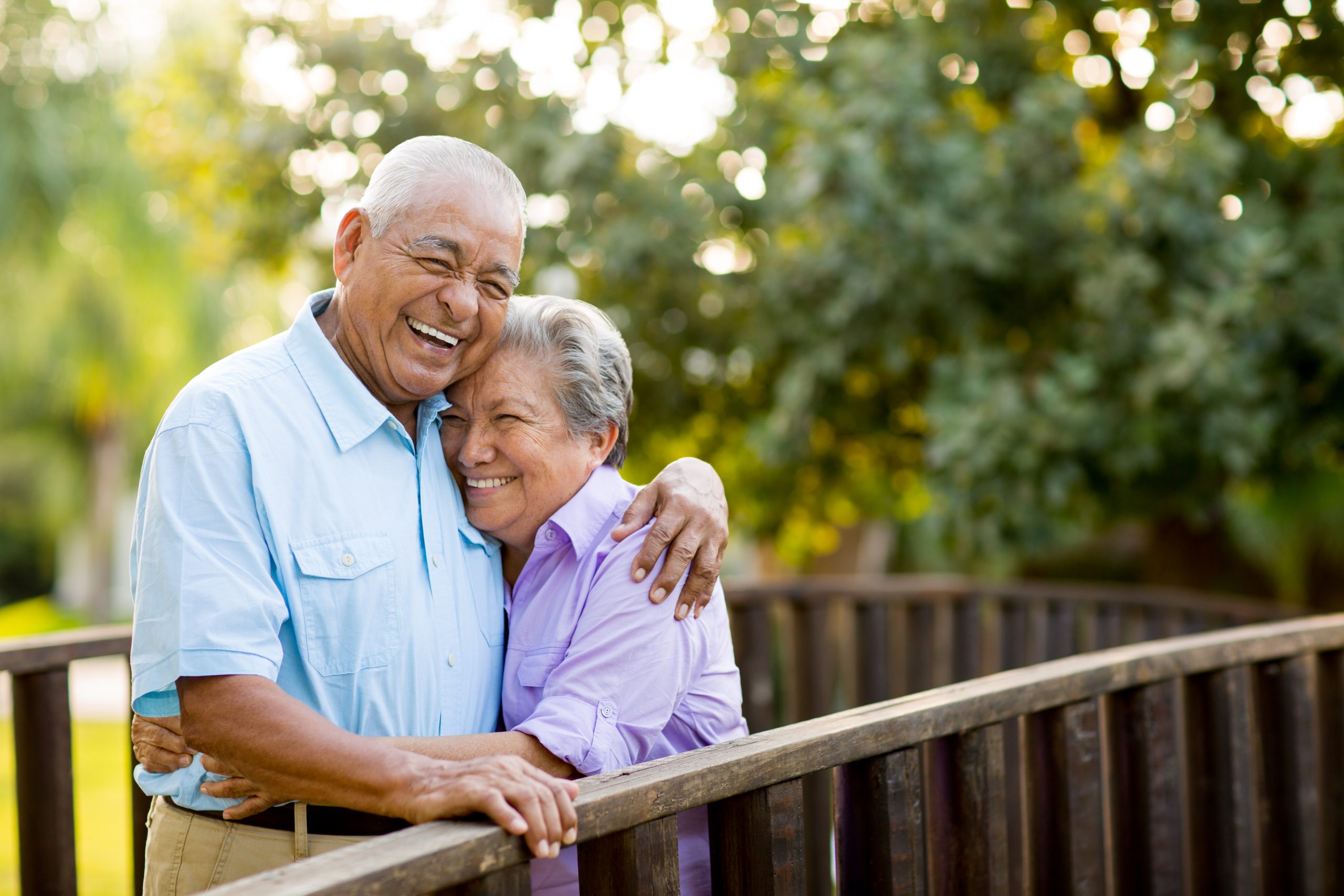 Senior couple laughing while embracing on outdoor bridge